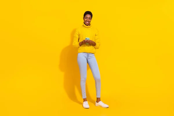Full length body size view of attractive cheerful skinny girl using device smm 5g app post isolated over bright yellow color background — Stockfoto