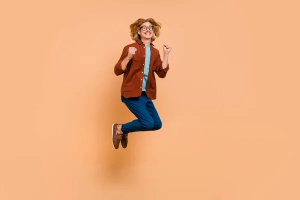 Full length body size view of attractive cheerful lucky guy jumping rejoicing having fun isolated over beige pastel color background — Stock Photo, Image