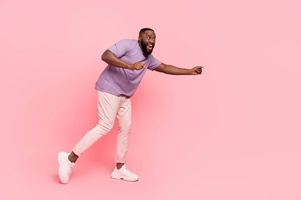 Photo of funny charming guy dressed violet t-shirt smiling dancing empty space isolated pink color background — Stock fotografie