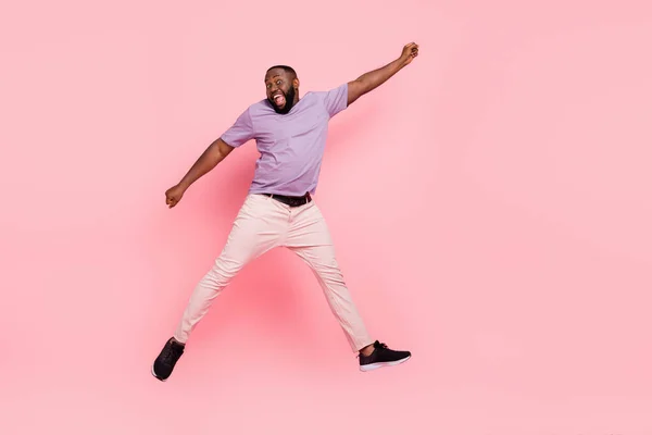 Взгляд в полный рост на привлекательного веселого сумасшедшего парня, прыгающего весело на розовом фоне — стоковое фото