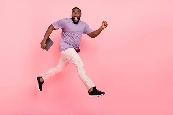 Foto de cara bonito animado vestido violeta t-shirt correndo segurando moderno gadget vazio espaço isolado cor de fundo rosa — Fotografia de Stock