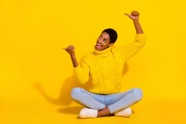 Portrait of attractive trendy cheerful girl sitting demonstrating copy blank space solution isolated on bright yellow color background —  Fotos de Stock