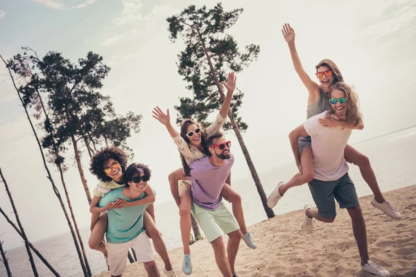 Foto de enganar brincalhão seis jovens amigos vestidos roupas casuais andando segurando braços piggyback ao ar livre campo — Fotografia de Stock