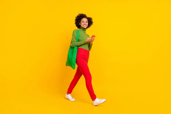 Teljes test profil oldalán fotó ifjúsági hölgy üzlet használata okostelefon séta lista elszigetelt sárga színű háttér — Stock Fotó