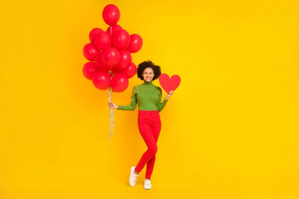 Full body photo of young cheerful girl hold many helium balloons present isolated over yellow color background — 스톡 사진