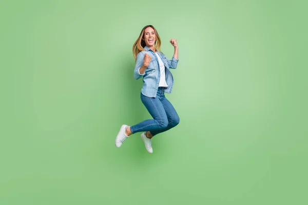 Foto de corpo inteiro de jovem senhora salto gritar desgaste camisa jeans sapatos isolados no fundo verde — Fotografia de Stock