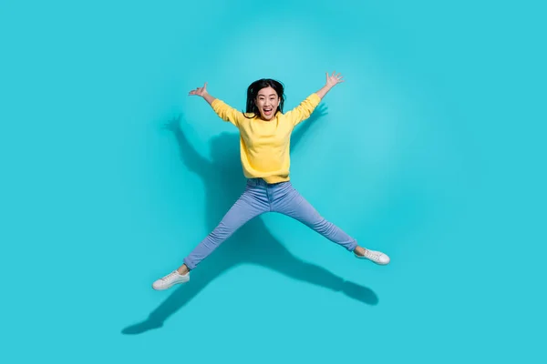 Full length photo of charming excited lady dressed yellow sweater jumping high like star isolated turquoise color background — Fotografia de Stock