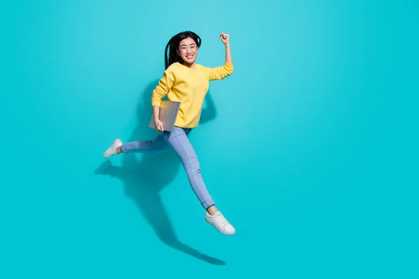 Full length photo of funny lucky lady dressed yellow sweater jumping runnig gadget empty space isolated turquoise color background — Zdjęcie stockowe