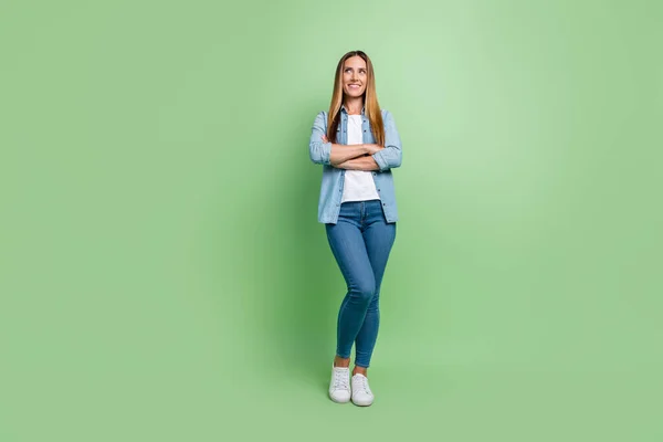 Full length photo of young lady crossed arms look promo wear shirt jeans sneakers isolated on green background — Stock Photo, Image