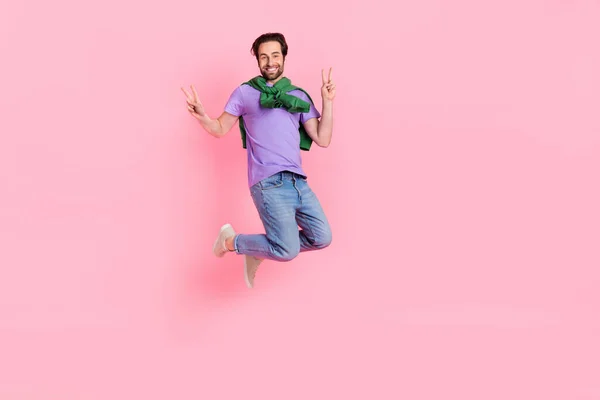 Full body image of overjoyed cheerful man flying show v-sign say hello greetings isolated on pink color background —  Fotos de Stock