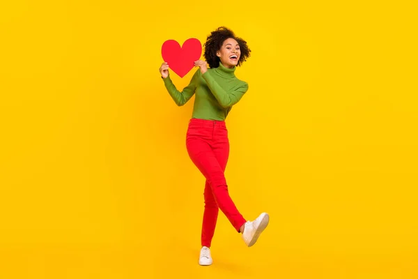 Teljes méretű fotó fiatal szép hölgy jó szórakozást tartani papír szív képeslap ajándék romantika elszigetelt sárga szín háttér — Stock Fotó
