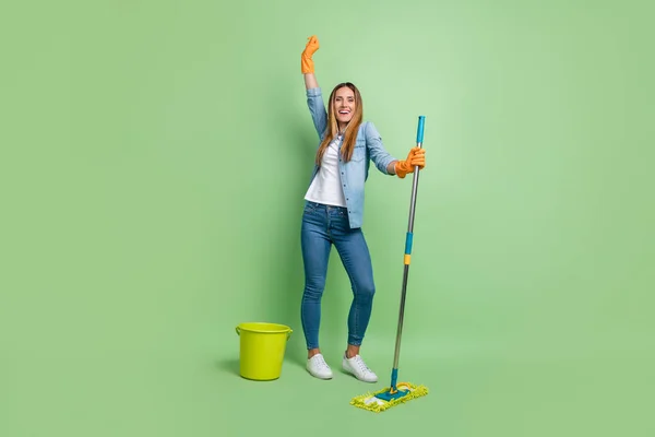 Full size photo of mature funny brown hairdo lady clean up yell wear shirt jeans shoes gloves isolated on green background — Stock fotografie