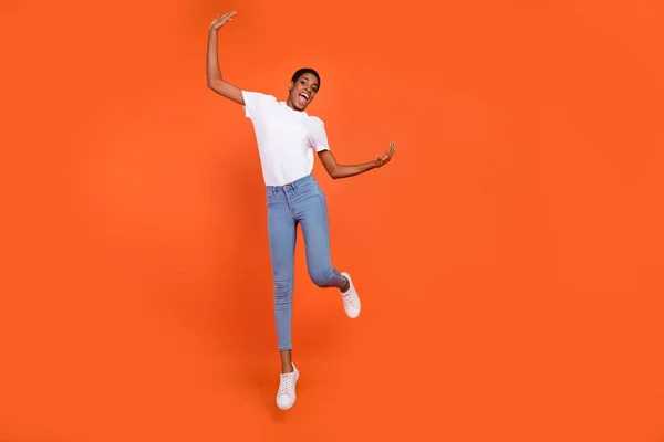 Full body photo of active androgyne lady jump up raise fist wear stylish t-shirt isolated bright color background — Stockfoto