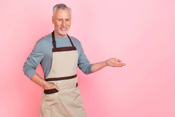 自信を持ってかわいい引退した男の写真は、灰色のシャツエプロン保持アーム空のスペース孤立ピンク色の背景を身に着けて — ストック写真