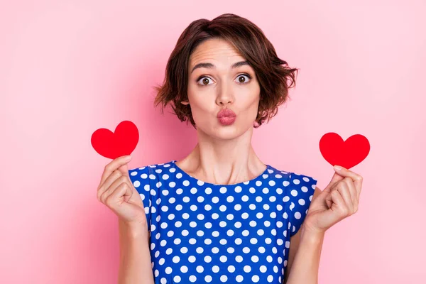 Photo of pretty young brunette lady hold hearts blow kiss wear blue blouse isolated on pink color background — Stockfoto