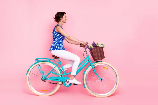 Full body photo of optimistic young lady ride bicycle wear blouse pants shoes isolated on pink background — Stockfoto