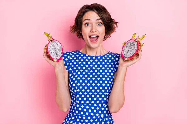 Foto di impressionato giovane bruna signora tenere drago frutta usura punteggiata camicetta isolata su sfondo di colore rosa — Foto Stock