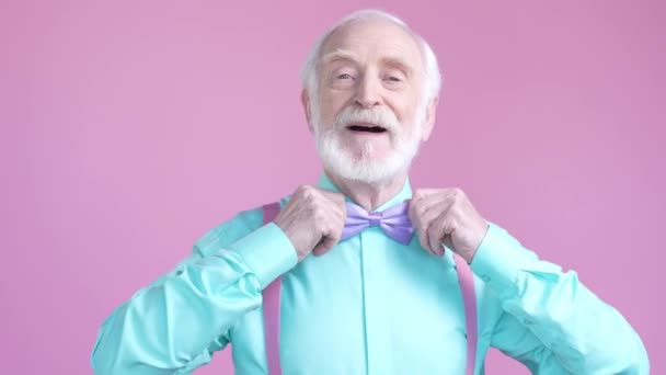 Okouzlující starý muž opravit správný motýlek izolované pastelové barvy pozadí — Stock video