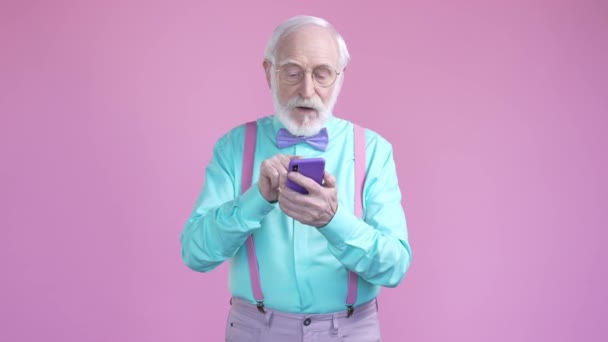 Aged man use smart device texting isolated pastel color background — ストック動画