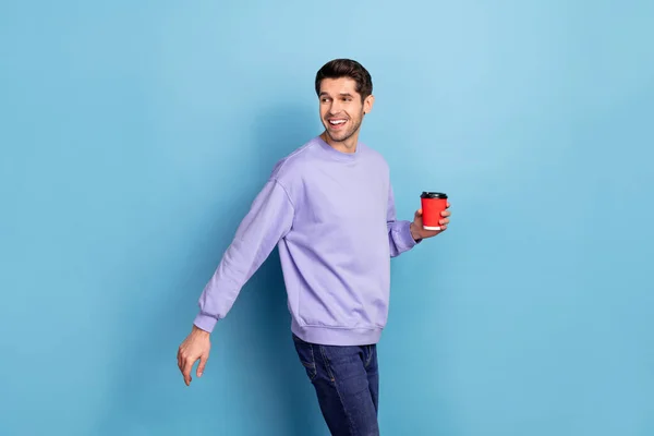 Photo of funny young brunet guy look promo drink americano wear pullover isolated on blue color background — Stockfoto