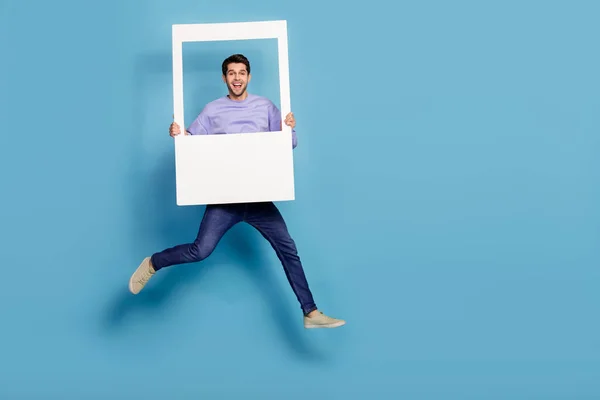 Full length body size view of attractive cheery guy jumping holding photo frame window isolated over bright blue color background — Fotografia de Stock