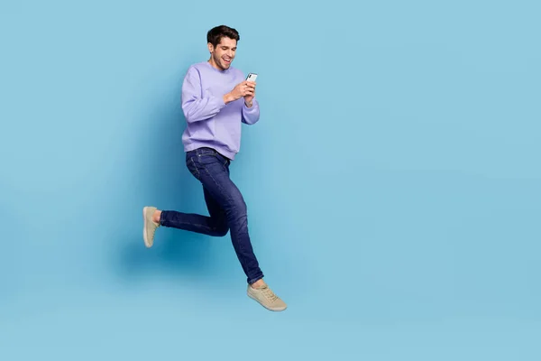 Photo of positive guy jump high use smart device hurry network discounts isolated blue pastel color background — Stockfoto