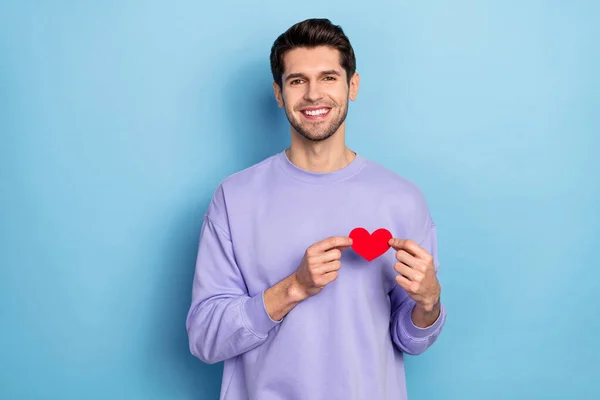 Photo of nice millennial brunet guy hold heart wear sweater isolated on blue color background — Fotografia de Stock