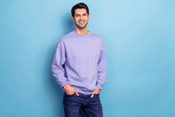 Portrait of attractive cheerful content guy holding hands in pockets isolated over bright blue color background — Stockfoto