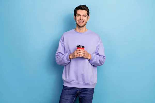 Photo of nice millennial brunet guy hold cappucino wear pullover isolated on blue color background — Stockfoto