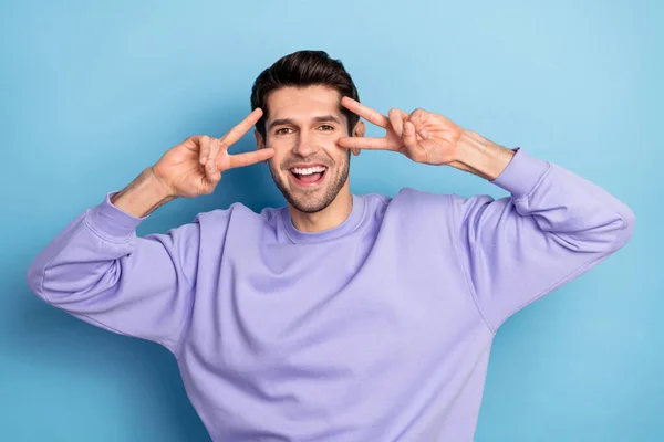 Photo of cool millennial brunet guy show v-sign wear sweatshirt isolated on blue color background — Stockfoto