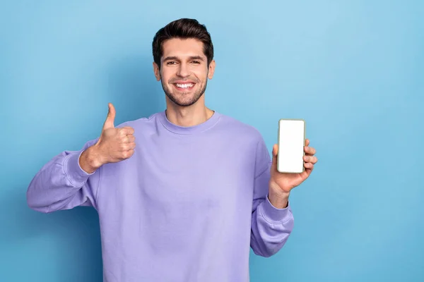 Photo of funny millennial brunet guy hold telephone thumb up wear pullover isolated on blue color background — Stockfoto