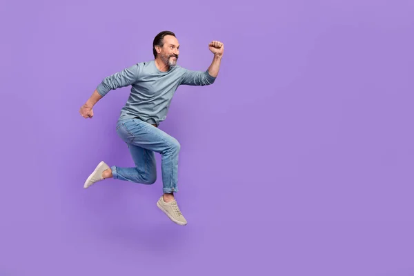 Ganzkörperprofil Seite Foto von reifen Mann laufen Sprung Eile Geschwindigkeit suchen leeren Raum isoliert über lila Farbe Hintergrund — Stockfoto