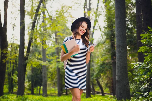 Portrait of beautiful cheerful schoolgirl holding book using device writing smm post pastime on fresh air outdoors — Fotografia de Stock
