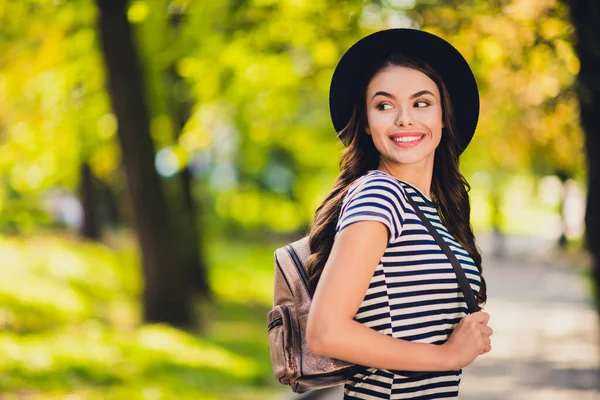 Photo of dreamy cute young woman dressed striped outfit cap backpack enjoying autumn season walking smiling outside landscape — Fotografia de Stock