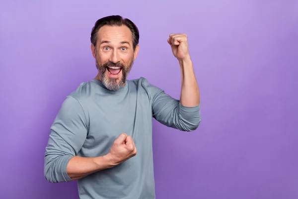 Foto von gut aussehenden fröhlichen Mann hebt die Fäuste in Errungenschaft triumphierenden Gewinn Preis isoliert auf violettem Hintergrund — Stockfoto