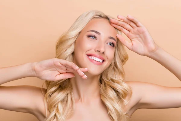 Portrait of attractive cheerful wavy-haired girl touching perfect skin uplift botox fillers isolated over beige pastel color background — ストック写真