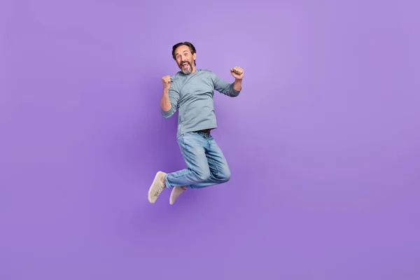 Full size photo of excited mature man celebrate luck fists hands jump up triumph isolated over purple color background — Photo