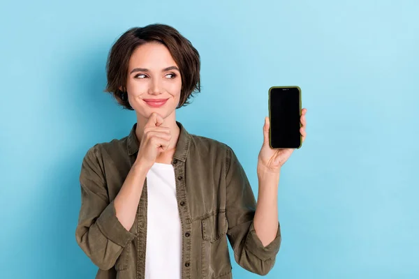 Photo of cute young short hairstyle lady hold look telephone wear khaki shirt isolated on blue color background — Stok fotoğraf