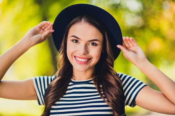 Photo of carefree charming young lady wear striped dress arms headwear smiling walking outdoors urban city park —  Fotos de Stock