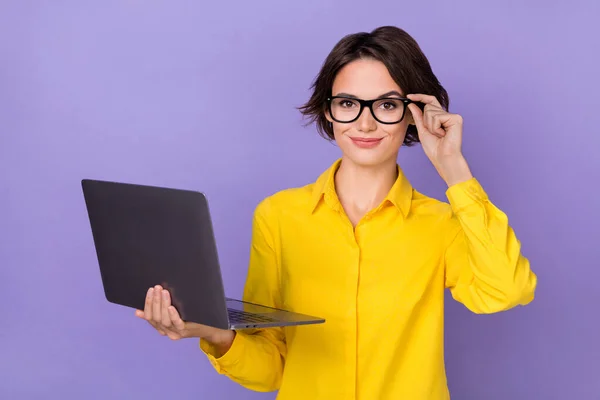 Fotografie ceo mladá bruneta dáma držet notebook nosit brýle žlutá košile izolované na fialové barvy pozadí — Stock fotografie