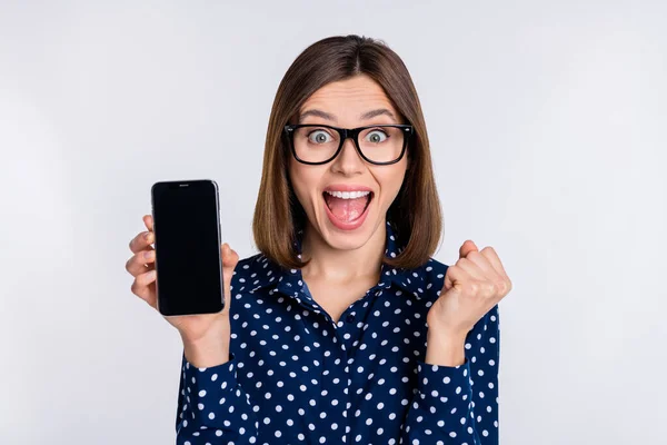 Photo of crazy lady hold phone show touchscreen empty space rejoice sale wear dotted blouse isolated grey color background — 스톡 사진