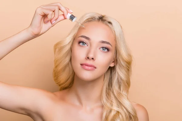 Photo of adorable woman apply moisturizing serum on forehead skincare routine isolated on beige color background — Stock Fotó