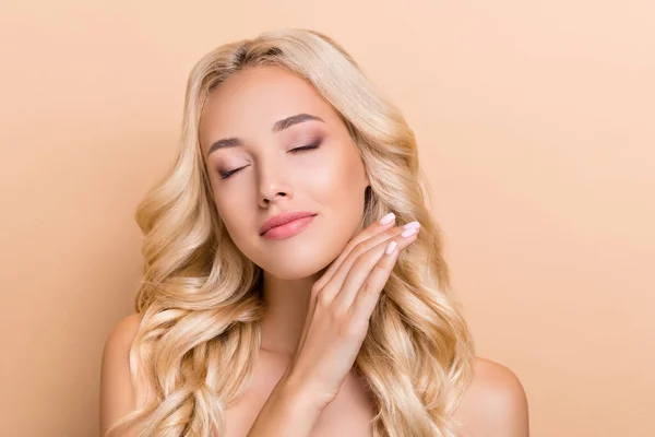 Portrait of attractive groomed dreamy wavy-haired girl touching soft skin hygiene isolated over beige pastel color background — 스톡 사진