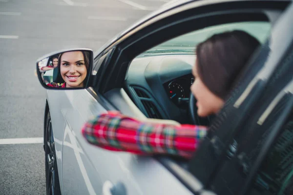 Porträtt av attraktiv glad flicka kör bil tittar på sidan spegel på parkering lärande studera kurser utomhus — Stockfoto