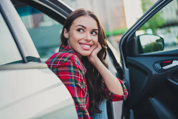Portrait of attractive cheerful wavy-haired girl passenger sitting in auto waiting husband shopping on parking outdoors — Foto Stock