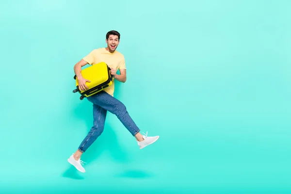 Full body photo of impressed brunet guy run with bag wear t-shirt jeans sneakers isolated on teal background — Stockfoto