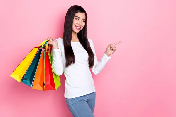 Photo of pretty young brunette lady hold bags index promo wear simple cloth isolated on pink color background — Stockfoto