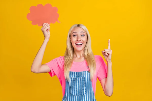 Retrato de chica alegre atractiva sosteniendo papel podría apuntar espacio en blanco copia aislado sobre fondo de color amarillo brillante —  Fotos de Stock