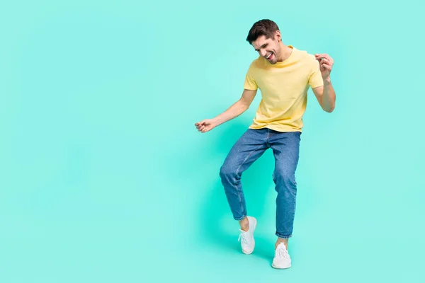 Full size photo of cute brunet young guy dance wear t-shirt jeans shoes isolated on turquoise background — Zdjęcie stockowe