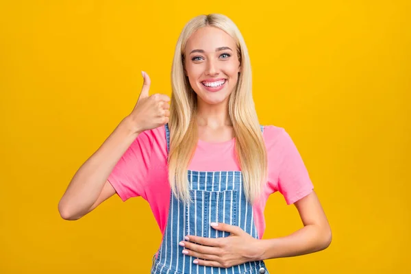 Portrait of attractive cheerful girl touching belly showing thumbup ad isolated over bright yellow color background — Fotografia de Stock